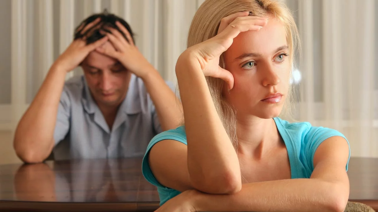 A man an a woman each holding their head in their hands, not speaking - marriage and relationship counselling