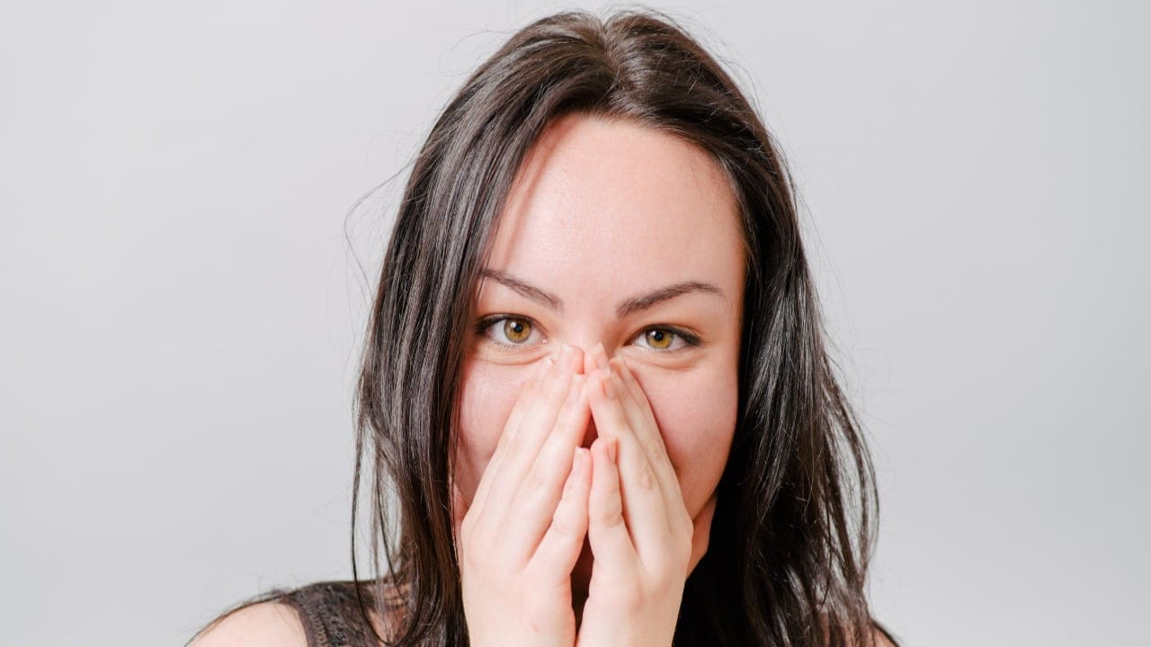 A woman blushing and hiding her face in her hands - 6 Top Tips to Avoid Blushing